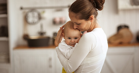  Besorgte Mutter hält ihr Baby liebevoll im Arm.