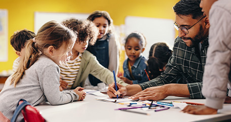 Ein Lehrer hilft einer Gruppe konzentrierter Kinder beim Lernen in einem lebendigen Klassenzimmer.